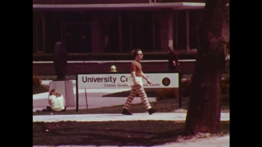 UNITED STATES: 1960s: highway research at university. Students outside university. Cars drive past building. 