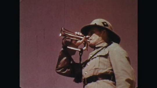 INDIA: 1960s: man in uniform blows bugle. Soldiers march in town square. 