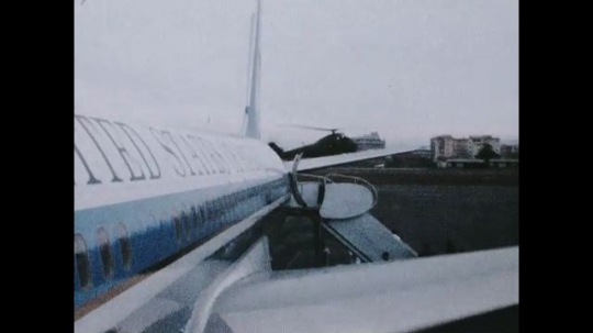 UNITED STATES 1960s: Side of Air Force One, helicopter landing in background / Helicopter on tarmac / Zoom in on helicopter, men gathering on tarmac.  