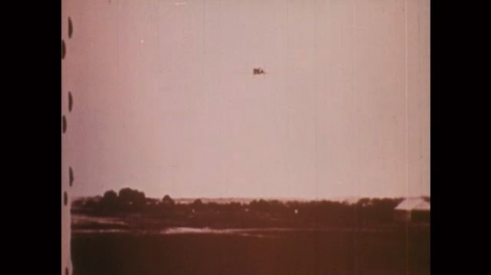 1910s: Airplane disappears over horizon. Men in military uniforms march in a line. Airplane in sky. Fleet of airplanes in sky. Explosions on battlefield, men falling. 
