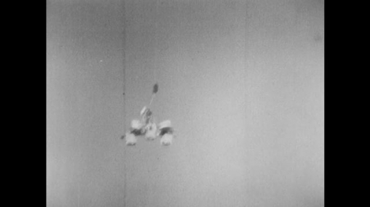 UNITED STATES: 1960s: space module falls from sky on parachute. Lunar module lands on ground. 