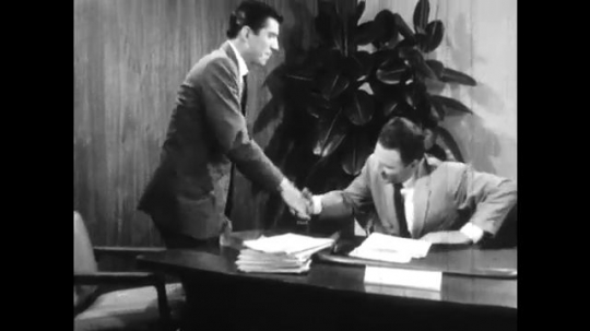 UNITED STATES: 1960s: men shake hands after meeting. Man smiles in corner of room. Man leaves office