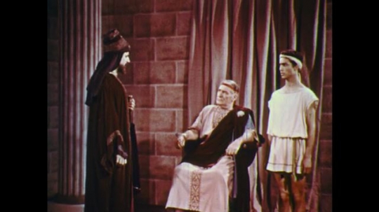 UNITED STATES: 1950s: man speaks to ruler on throne. Boy leaves. 
