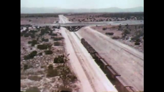 UNITED STATES: 1970s: overhead view of train passing under roads. 