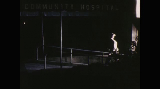 UNITED STATES: 1960s: police man leaves hospital. Officer walks to police car