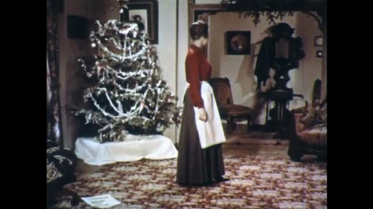 UNITED STATES: 1950s: lady takes off apron in room. Lady speaks up stairs. 