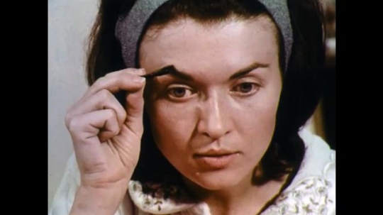 UNITED STATES: 1960s: lady brushes mascara into eye brows.
