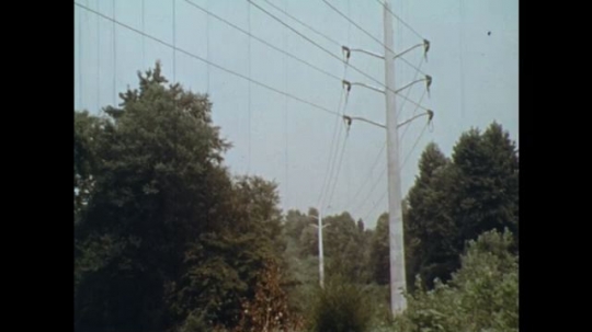 UNITED STATES: 1970s: Telegraph pole and line through woods. Building frame made from wood. Man works on building site. Printed paper. 