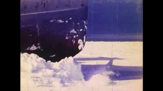1970s: UNITED STATES: close up of icebreaker ship at sea. Boat breaks through ice. Ice viewed from underneath. Submarine under ice