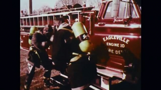 1950s: UNITED STATES: buildings on fire. Firefighters spray hoses on building blaze