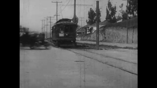 1920s: police car races cuts off trolley, hits fire hydrant and ejects men into spray. reckless car drives down street, bumps vehicles and smashes into a store. motorcycle rides up stairs.