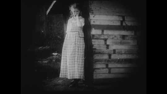 1910s: Young girl cries next to a shed. A group of adults and two young adults meet in a parlor. The two young adults are left alone and laugh together.