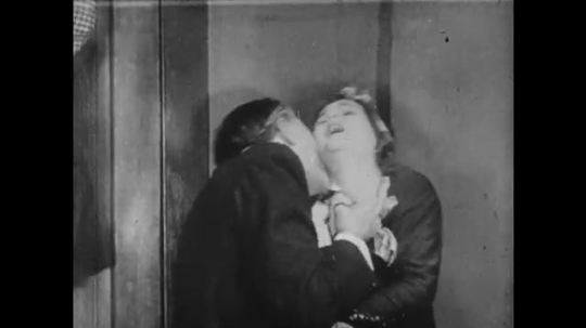 1910s: Man kisses woman on the neck, she doesn