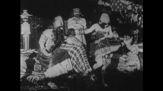 1910s: UNITED STATES: man sits on throne. Man attacks servant. People fight on city walls
