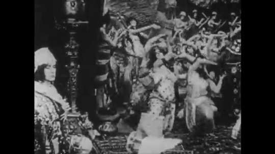 1910s: UNITED STATES: people dance for man. Lady dances by man on throne. Ladies lie on floor