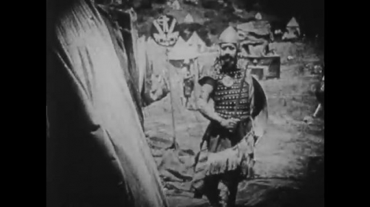 1910s: UNITED STATES: guard stands outside tent. Goblet falls. Lady stands by body. Lady in cloak outside tent. Lady drops sword. Lady gets scared. Lady stands outside tent