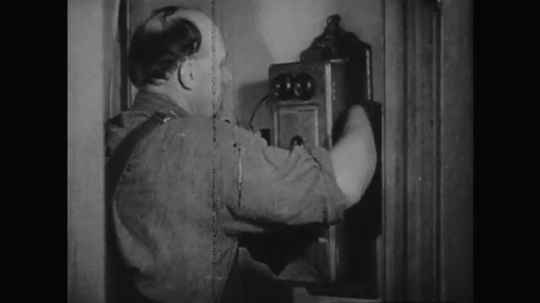 1930s: Man talks on phone. 