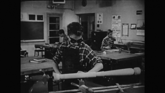 1950s: Boy works with equipment. Boy in class. Man speaks to boy. Boy speaks. Boy chisels wood.