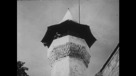 1960s: Man yelling from minaret. Men praying. Man kneels. Man prays in mosque. 