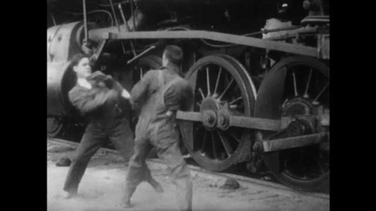 1910s: Men in fist fight. Other men and woman come up and break up fight. Man yells in other man