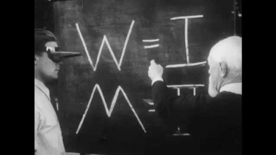 1950s: Professor and man with special glasses look at blackboard, hand comes and goes out with pendulum. Professor and man with head covered, hand turns light switch off, professor holds head of man.