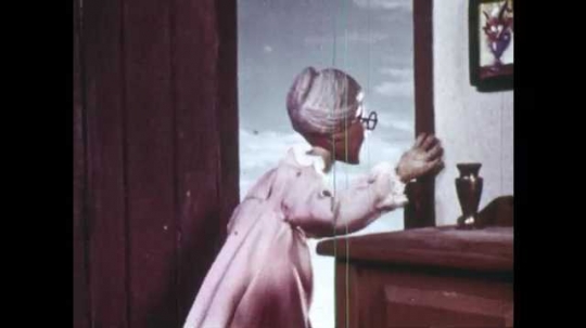 1940s: Animation of grandmother who stands at front door. She looks outside, puts hands on chest and head. Red Riding Hood runs down stairs, they hug, grandmother pats her head. Hunter pats his rifle.
