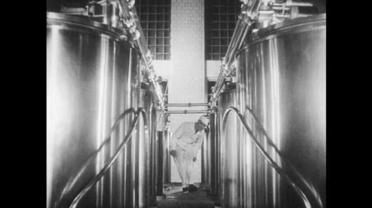 1930s: A man in coveralls examines large metal tanks in a plant. Bottles move through a machine as they are pasteurized. In a historical reenactment, a man sprays antiseptic in an operating theater.