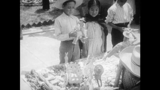 1930s: Boy picks out and buys toys.  Man makes toy wiggle.  Girl looks at table.