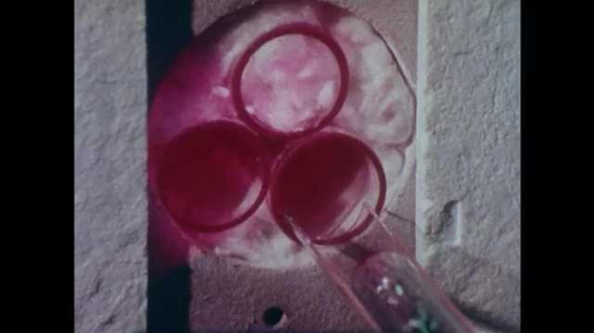 1980s: Close up, glass tube slides into machine. Glass tube slides out containing crystal. 