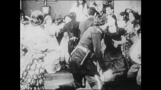 1910s: women in dresses and men in civil war union soldier uniforms dance, slap hands to a beat and exit a living room. crowd near house cheers and waves flag as Northern soldiers march on road.
