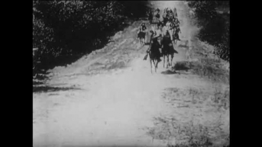 1910s: men on horses and wagons race down dirt road. Confederate troops creep near rocks. Blast at door knocks down Union soldiers in living room. Cannons fire on wall. title card about powder wagons.