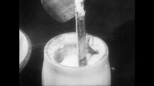1940s: Mother pulls butter out of churn on dasher. Mother removes butter from dasher and puts it in wooden bowl. 