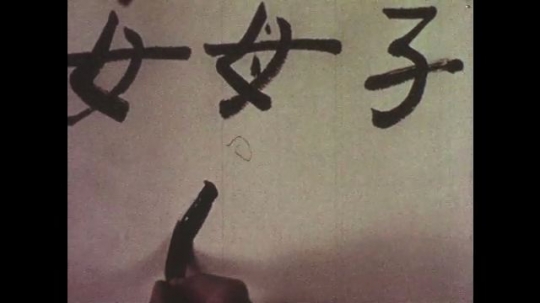 1950s: Close up, hands draw Chinese characters. 