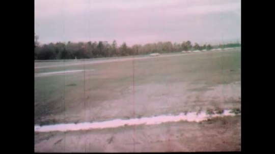1960s: Race cars speed down track.  Spectators watch.  