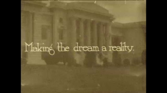 1920s: Title card superimposed over building entrance. Workers plow field in front of building. Man in suit talks to children with paper in his hands. Children move plants.