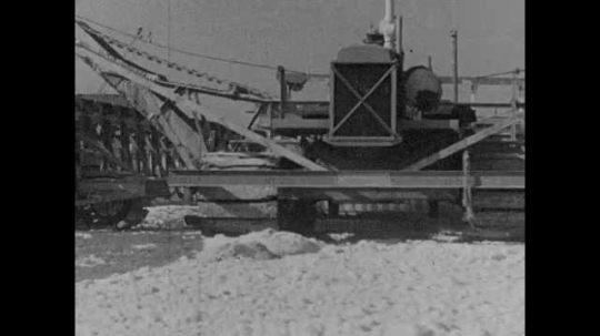 1920s: Machinery operates at a salt company. A screw conveyor moves the salt toward a conveyor belt.