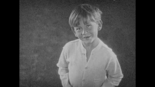1920s: Boy looks up and smiles.  Head appears in air above body.  Face smiles and speaks.  Dog barks.