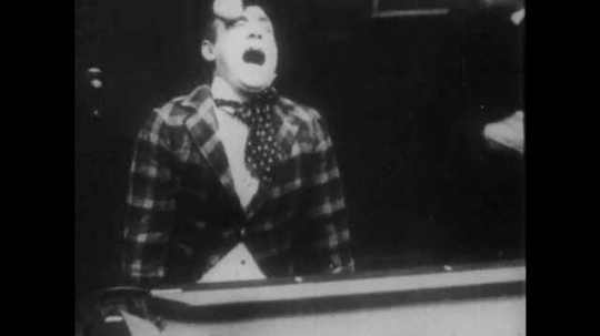 1910s: A cue ball hits a man in the eye. A man hits him with a pool cue as a crowd gathers. He takes another shot. The balls go in the holes, then return to their original formation.