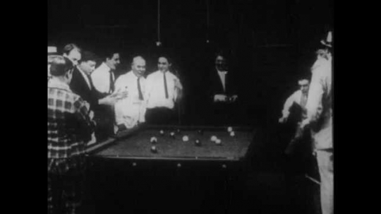 1910s: A man dumps a handful of pool balls on the table, disrupting the game. The crowd chastises him and resets the rack. His competitor breaks the rack and sinks every ball.