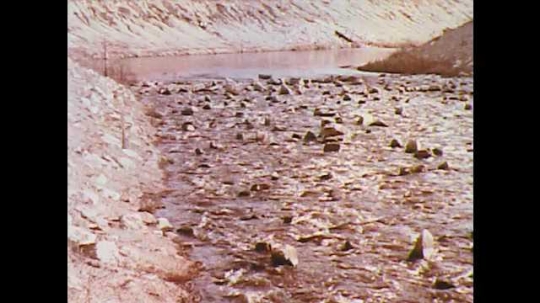 1970s: UNITED STATES: water in river. Water flows over rocks. Water in industrial plant. Men prepare water tanks. Water flows in stream